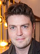 A photograph of Tom Burke