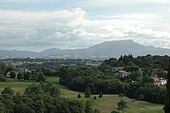 Vue d’un golf sur fond de montagnes.