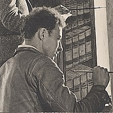 man with curly hair painting a mural on a wall