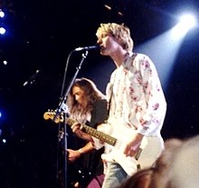A sideview of two rock musicians performing onstage.
