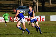 Sydney AFL league East Coast Eagles AFC player uses a handball pass to dispose of the ball before he is tackled by a Campbelltown Kangaroos AFC opponent.