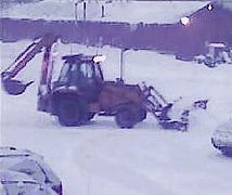 A backhoe with a snow plow attachment clearing snow