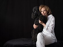 Georgina Montagu wearing white trousers and shirt with her previous black standard poodle Albert