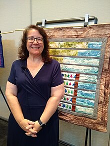 Laura Guertin pictured with a science-themed quilt