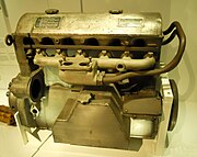 Maybach HL42 TRKM (intake side) with most ancillaries removed. Oil reservoir (TR dry sump) at lower centre; intake manifold and twin vertical holes for carburetter (centre); some of the clutch mechanism (K) partly obscured (far left); the magneto (M), driven off the flywheel, fits in the large hole to the left of the oil reservoir;[v] the fuel pump attaches to the two threaded studs directly below.