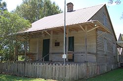 A raised wooden cottage with a large front porch.