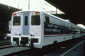 A white passenger rail car with a wide black stripe and thin red, white, and blue stripes