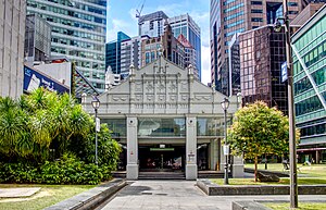 A colonial-style entrance of Raffles Place station, surrounded by various commercial buildings