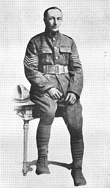 Full length portrait of a soldier in service dress uniform leaning against a table