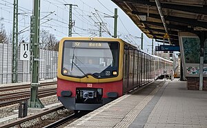 Boxy red-and-yellow train next to a platform