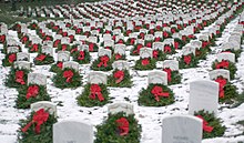 Thousands of balsam fir Christmas wreaths with red ribbons propped against headstones in a snowy Arlington National Cemetery in Arlington, Virginia, in the U.S.