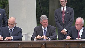 Bill Clinton watches Hussein of Jordan and Yitzhak Rabin signing papers