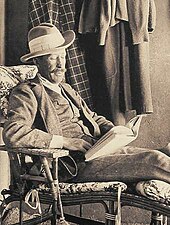 A man in early twentieth-century clothes seated and reading