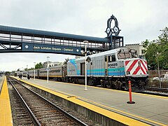 A locomotive painted gray with turquoise and light blue stripes and a curve towards the top rear of the locomotive, with red chevron stripes on the front.