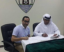 two men sitting at a desk signing papers