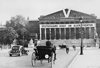 Horse-drawn coaches in front of the National Assembly, decorated with slogan: "Germany is winning on all fronts" (Bundesarchiv)