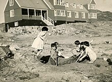 Six children playing in the dirt beside an orphanage