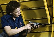A woman uses a drill powered by compressed air.