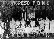 Group of 11 women standing behind a table below a banner proclaiming "For Life and For Peace"