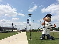 Walkway leading to Four Winds Field at Coveleski Stadium, pictured in July 2015. There is an inflatable display of the South Bend Cubs mascot, Stu, holding a sign advertising a game to be played that day.