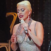 Lady Gaga in a sparkly outfit with a microphone in her hand