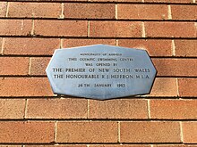 A stainless steel plaque on a brick wall, located at Ashfield Pool, opened by NSW Premier, R.J. Heffron, 26 January 1963.