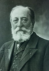 bust-length portrait of Saint-Saëns with a beard in a vest and suit, looking at the viewer