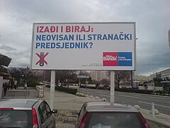 Billboard in parking lot, with blue and red letters on white background