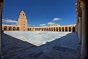 Photographie de la cour, vue depuis son angle sud-ouest. Le portique septentrional est interrompu, vers son milieu, par le minaret.