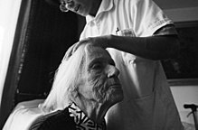 An old woman having her hair brushed