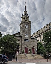 Color photo of an urban granite church flanked by small gardens