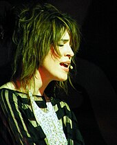 Imogen Heap singing onto a mic with her eyes closed