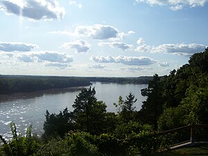 A wide river flows between dark forests and low bluffs