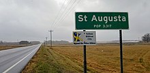 road sign reading "St. Augusta, population 3,317" and "Yellow ribbon city", in front of a harvested corn field