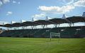 Photo from behind the goal. Green seats under a roof.