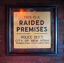 A framed sign on a brick wall. It reads, in all capital letters, "This is a Raided Premises. Police Dep't. City of New York. Howard R. Leary. Police Commissioner".