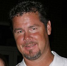 A smiling man with short curly hair and a salt-and-pepper goatee