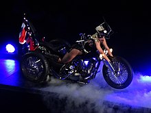 Lady Gaga on top of a motorcycle as if she were it.
