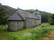 View of the stone apse and north wall of the church, with gravestones in the background