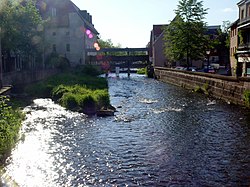 A river flowing through a town. In the background there is a bridge.