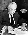 A grim Franklin D. Roosevelt signing the declaration of war against Japan.