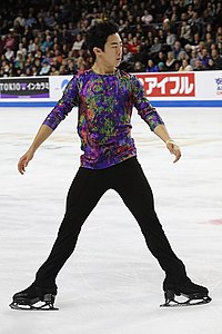 A photograph of Nathan Chen performing a spread eagle on the ice.