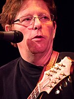Bluegrass singer Tim O'Brien, singing into a microphone while holding a mandolin