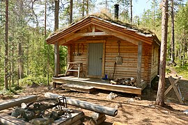 Chalet en bois située dans une forêt de conifères et entouré d'outils en bois.