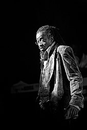 Black and white image of a man with dreadlocks wearing eyeglasses.