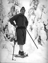 Un homme en tenue d'hiver avec des skis au pied et des bâtons dans les mains.