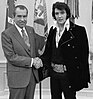 Two men shaking hands in front of flags