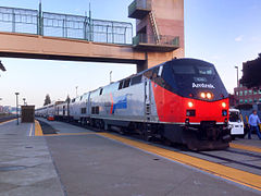 A gray diesel locomotive with black cab area, red on the lower front end, black underside, and Amtrak logo on the side