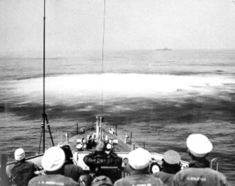 A large white upwelling of water from an underwater explosion just ahead of Moberly's bow following Hedgehog launch[12]