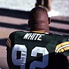 Photo of the back of Reggie White sitting on the sideline in his uniform with no helmet
